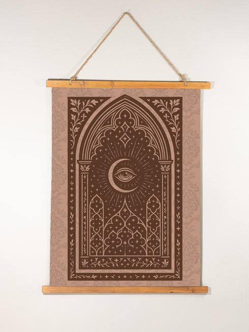 A large, luxurious tapestry in muted mauve and brown, featuring a Gothic arch design. In the center, a crescent moon holds an All-Seeing Eye that radiates light. The design is filled with intricate patterns like quatrefoils and stars, creating a mystical, esoteric feel. The fabric has a subtle damask texture and is hung from wooden dowels. This piece is suitable as spiritual wall art, a witchy altar cloth, or dark academia decor, blending celestial and gothic aesthetics.